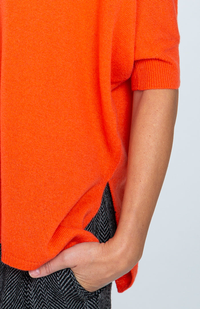 Maxi maglia scollo v in puro cashmere con manche corte, color arancio, dettaglio manica e spacco laterale.